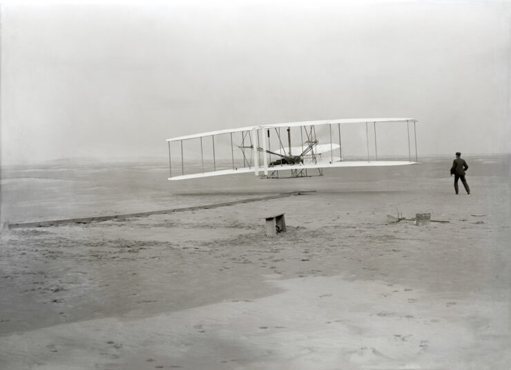 The first powered, controlled, sustained airplane flight in history. Orville Wright, age 32, is at the controls of the machine.